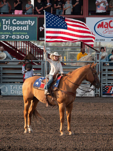 Rider carrying the American flag on horseback in the arena