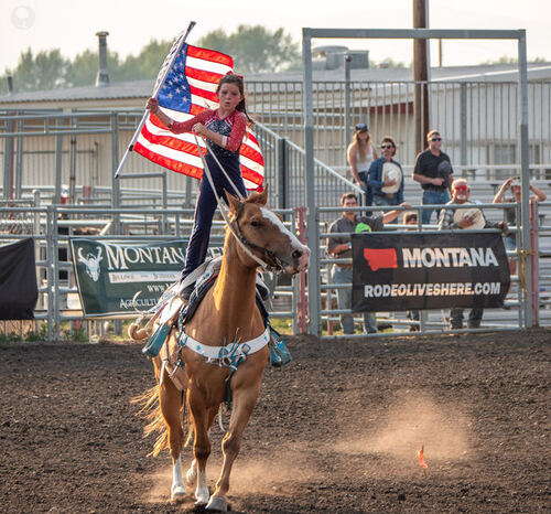 Flag rider circling the arena through the dust